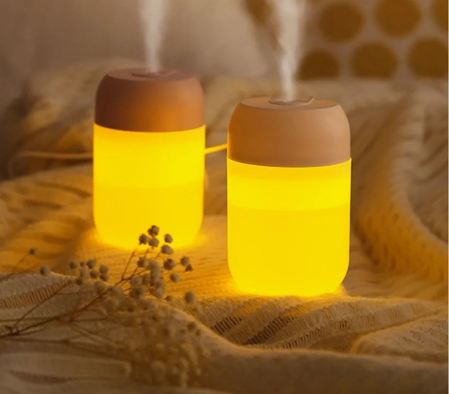White cylindrical USB mini humidifier with charging cable on wooden desk