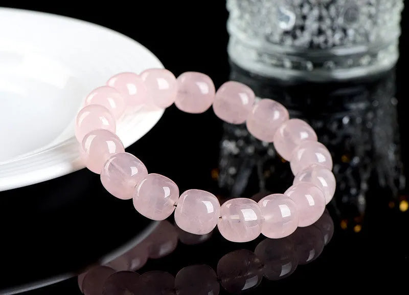 Close-up of a pink geometric bracelet with barrel-shaped crystal beads on a wrist.