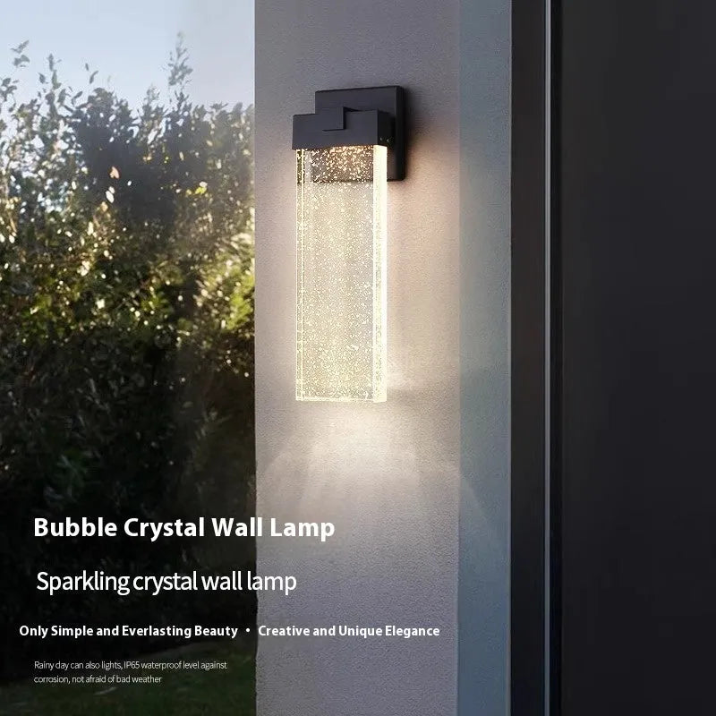 Black stainless steel outdoor LED wall lamp mounted on a wall, showing its rectangular shape and warm light emission.