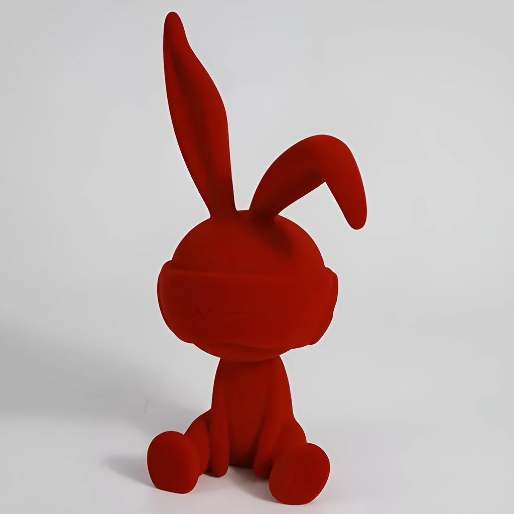 Green resin rabbit table ornament with suede blindfold on wooden surface