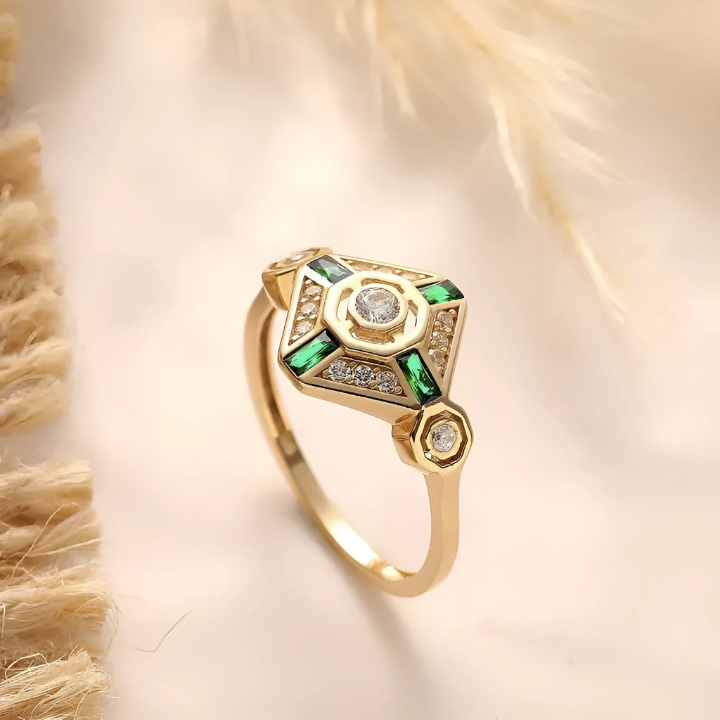 Square-shaped gold tone ring with emerald diamond colour on a model finger.