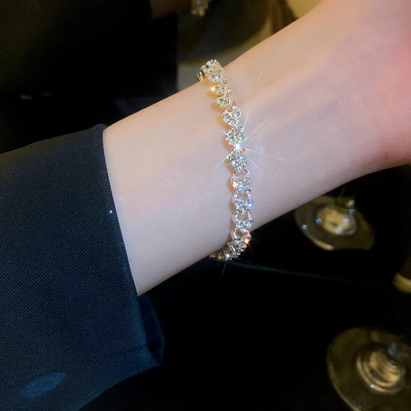 Silver metal heart-shaped bracelet with inlaid zircon on a plain background