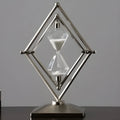 Glass sand clock timer with detailed metal ornaments in a bronze finish, showing modern simplicity style.