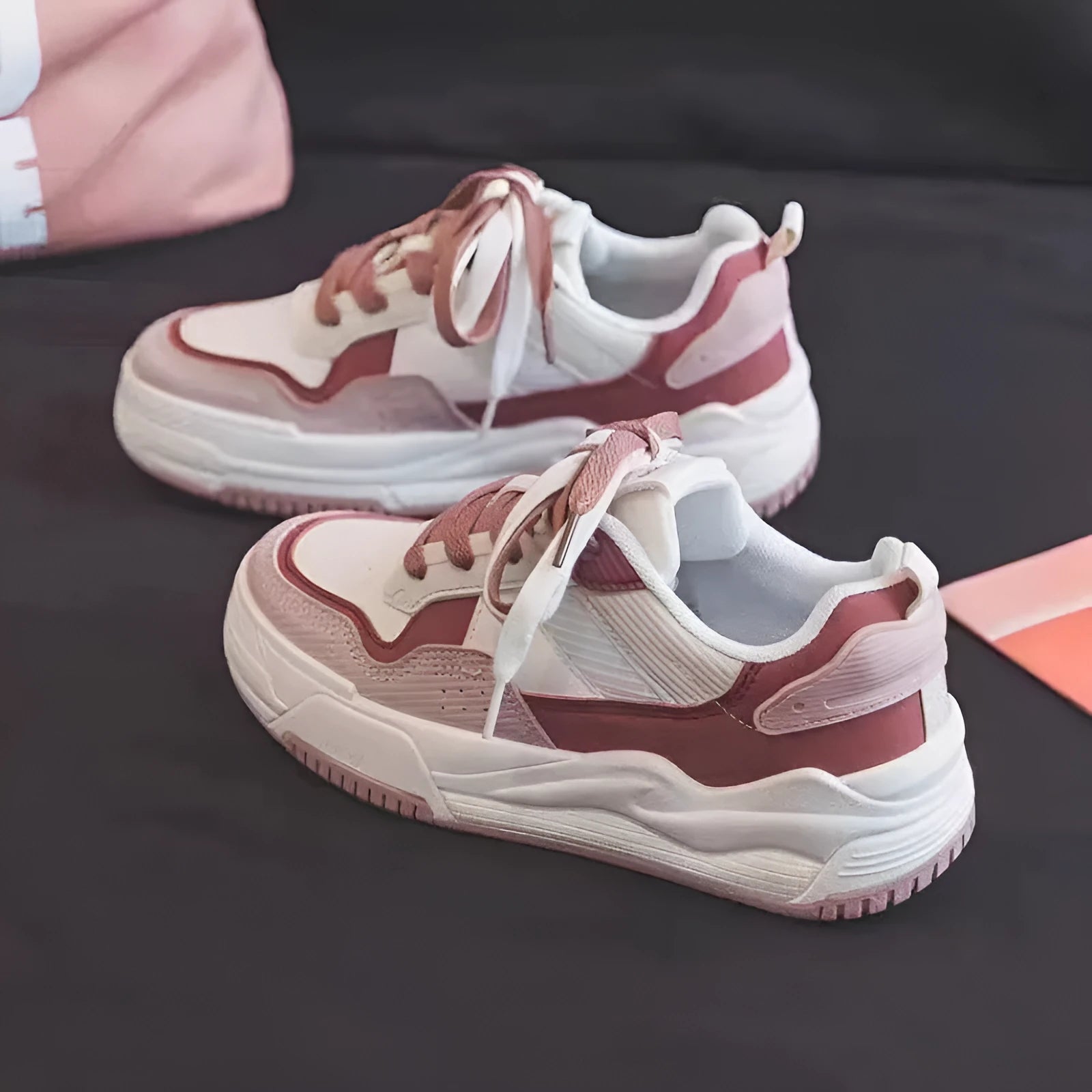 Women's pink and white low-top sneakers with a height-increasing rubber sole on a neutral background.
