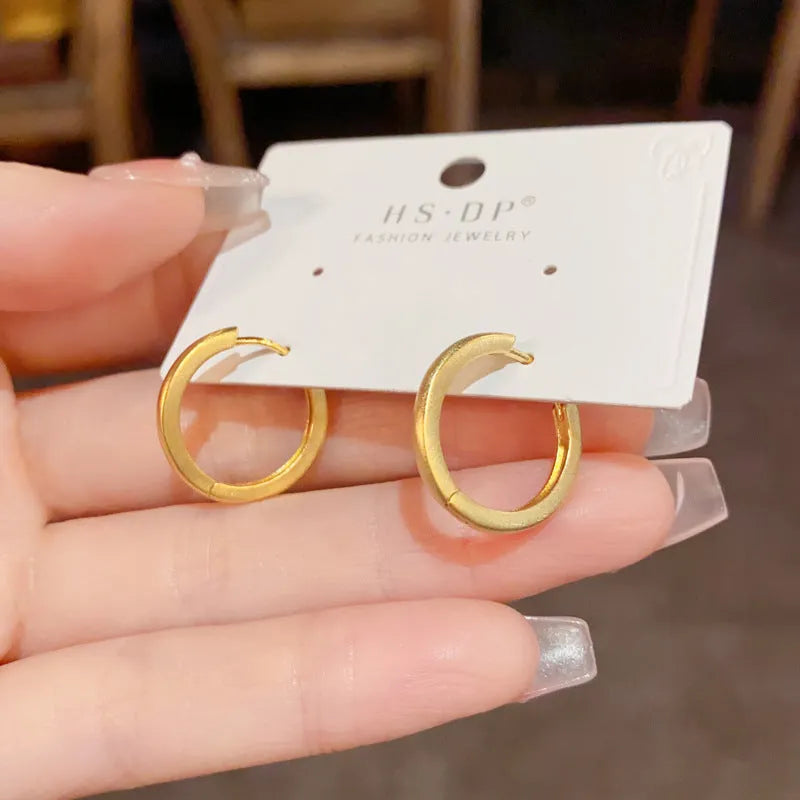 Women's geometric round eyelet ear clips in gold and silver colours, showing front view.