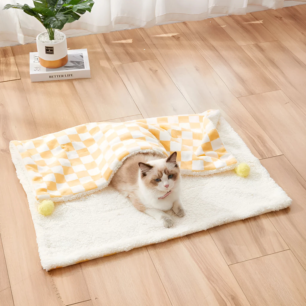 Soft plaid pattern pet blanket with fur ball decoration on a sofa