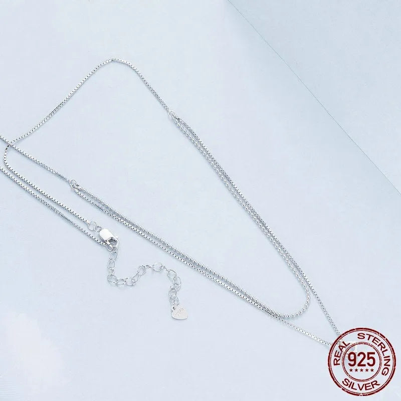 Close-up of a double-layer sterling silver necklace with a pearl-style chain, showing its layered design and silver finish.