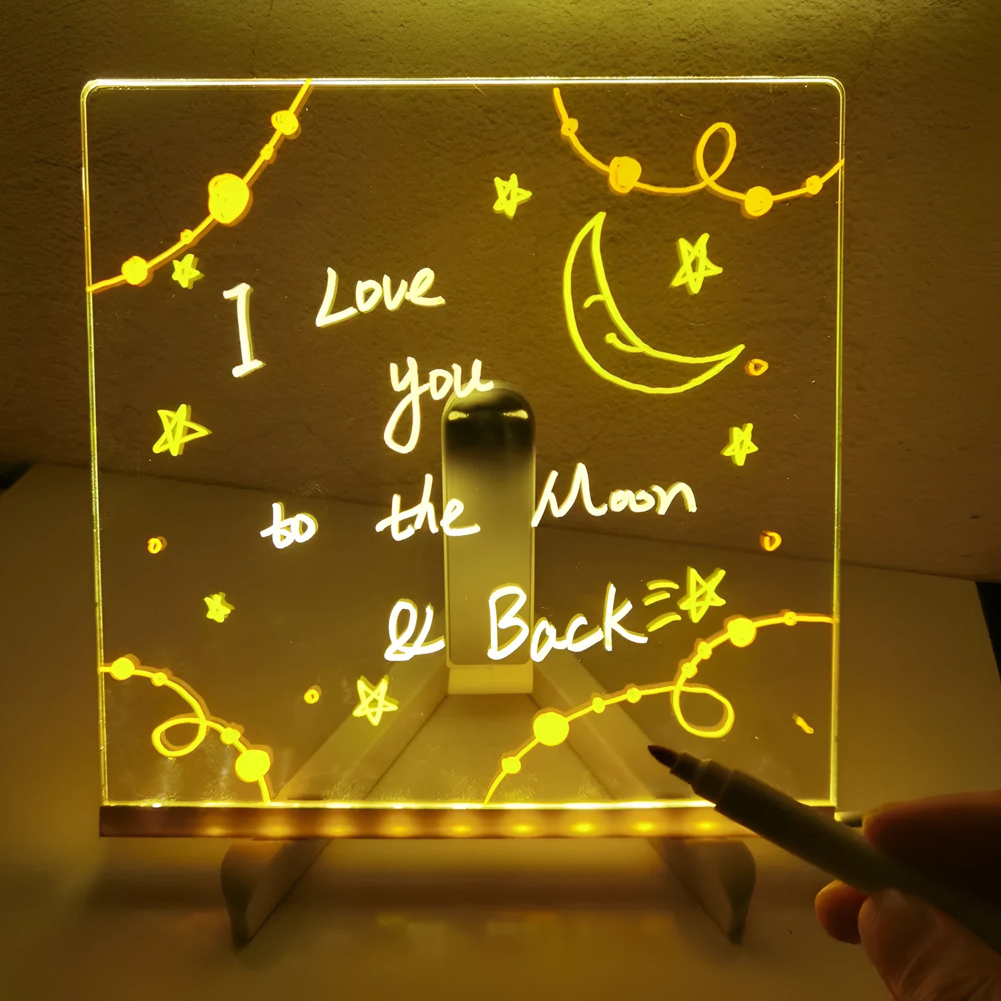 DIY acrylic LED message board lamp on a desk with colourful writing, showing USB cable and pens.