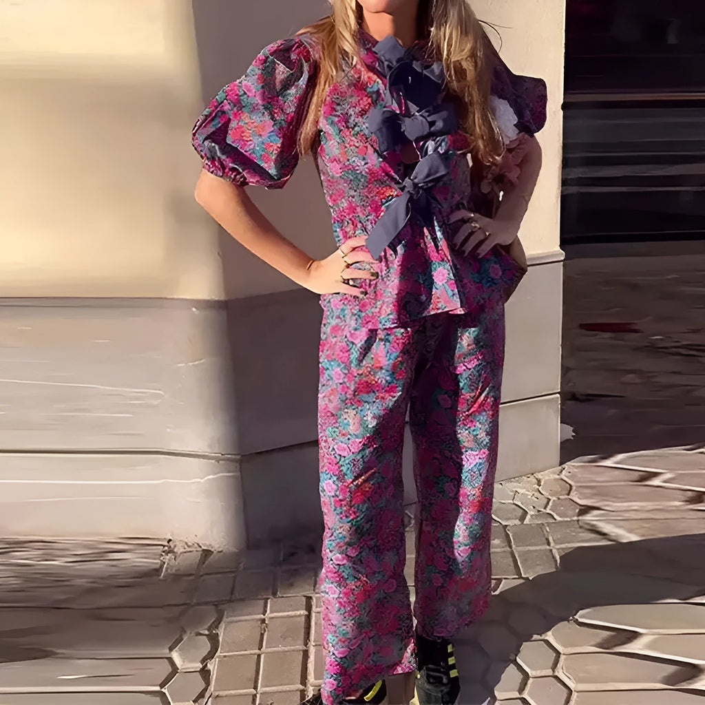 Women's floral print polyester trouser suit with tie-neck top and puff sleeves.