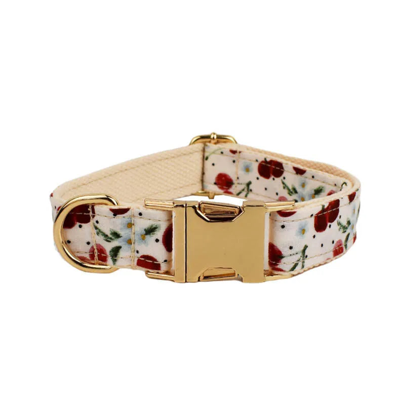 Red cherry print dog collar and leash set with light gold buckle, matching vest, bow, and poop bag holder.