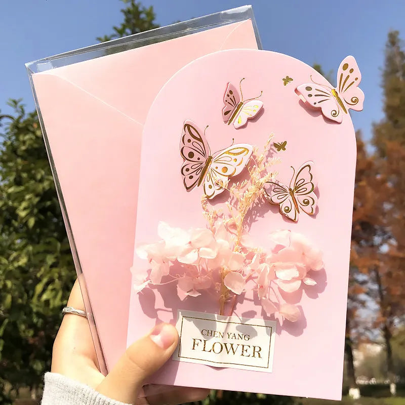 Handmade 3D butterfly-shaped greeting card with artificial flowers in a box, alongside its matching envelope.