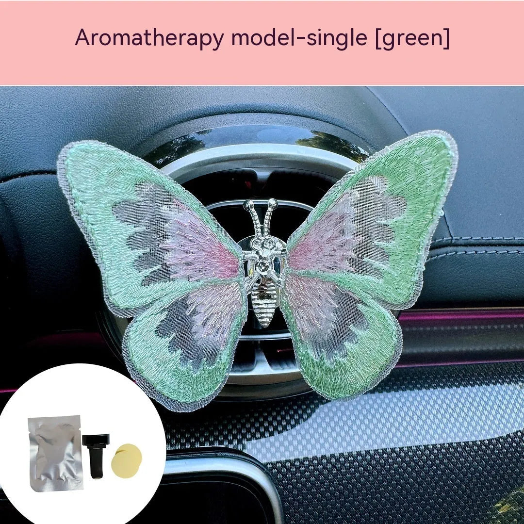 Fabric embroidered butterfly car air vent decoration in multiple colour options on a dashboard.