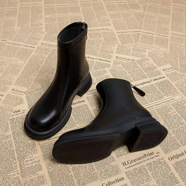 Women's black ankle boots with a flat thick heel, round toe, and rear zip fastener on a white background