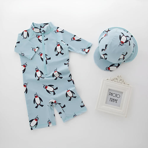 Boys' blue and white penguin print long sleeve swimsuit with matching swimming cap laid flat.