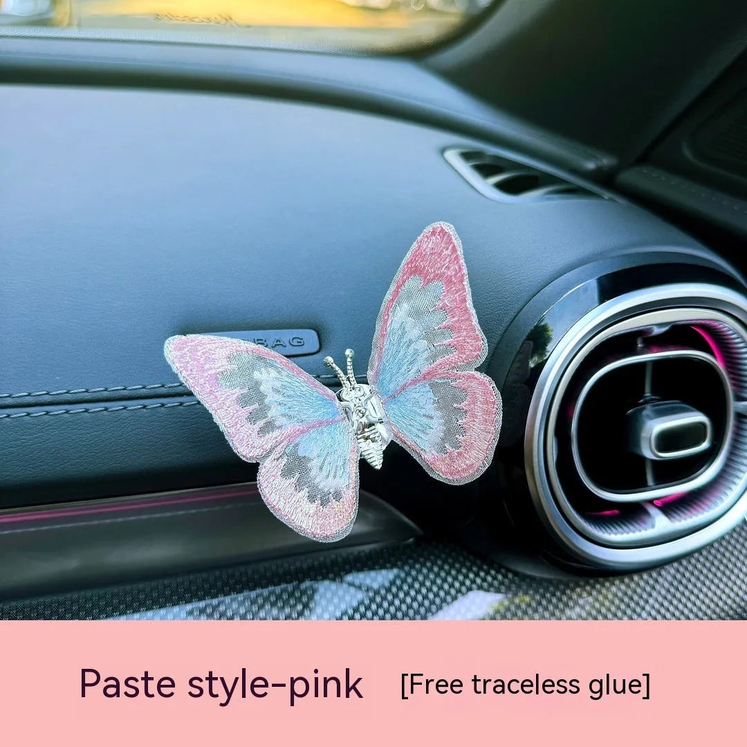 Fabric embroidered butterfly car air vent decoration in multiple colour options on a dashboard.