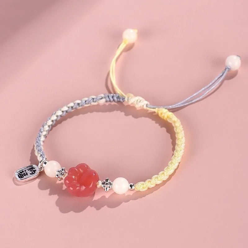 Red cat's paw glass bead on a handmade pink woven bracelet for couples.