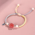 Red cat's paw glass bead on a handmade pink woven bracelet for couples.