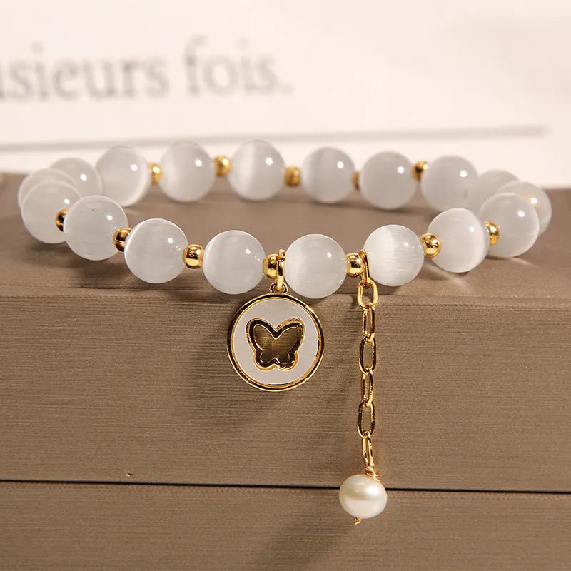 White Cat's Eye crystal bracelet with geometric links on a wrist.