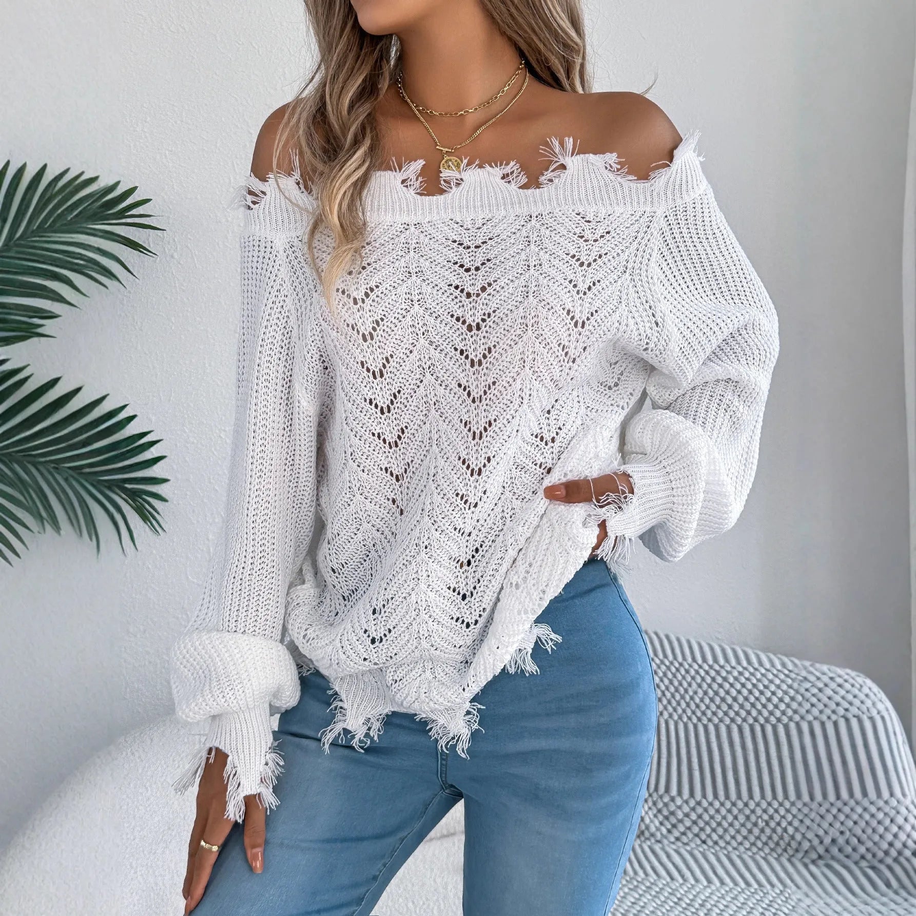 White cut-off-shoulder pullover sweater with hollow-out long sleeves on a mannequin.