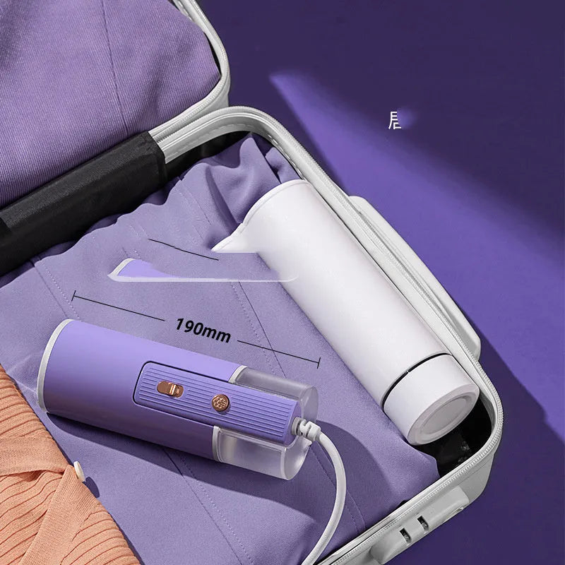 Foldable handheld clothes steamer in grey lotus root purple on a table.