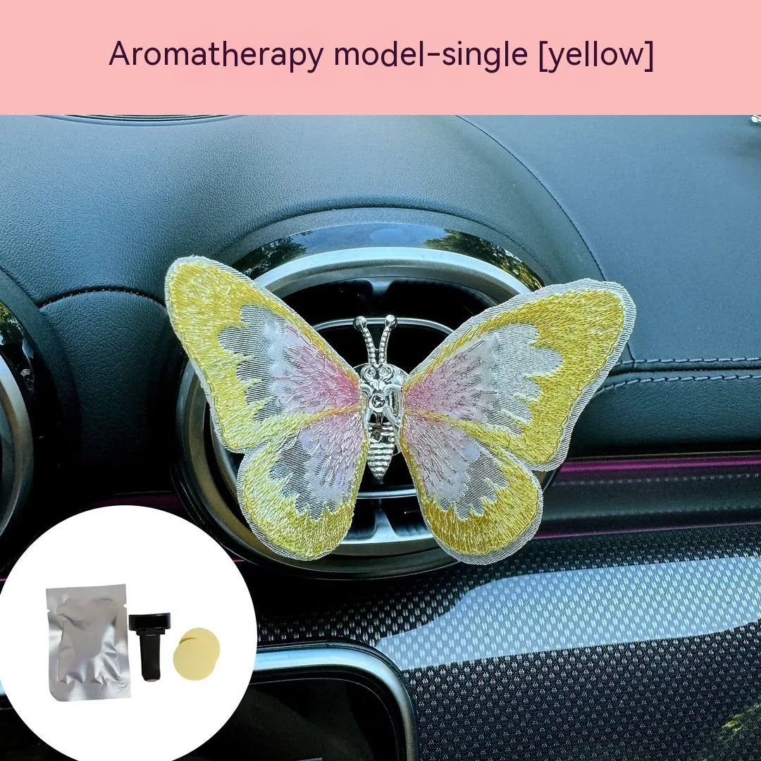 Fabric embroidered butterfly car air vent decoration in multiple colour options on a dashboard.