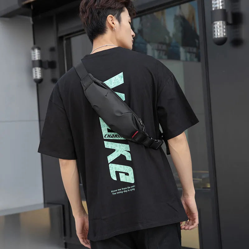 Men's black Oxford cloth crossbody waist pack showing front zipper and compact dimensions