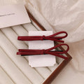 Wine red leather bow design hair barrettes on a white background.