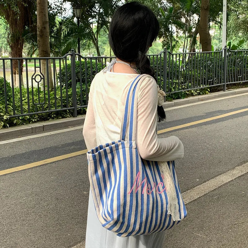 Blue, pink, and white striped canvas bag with printed letters on the front.