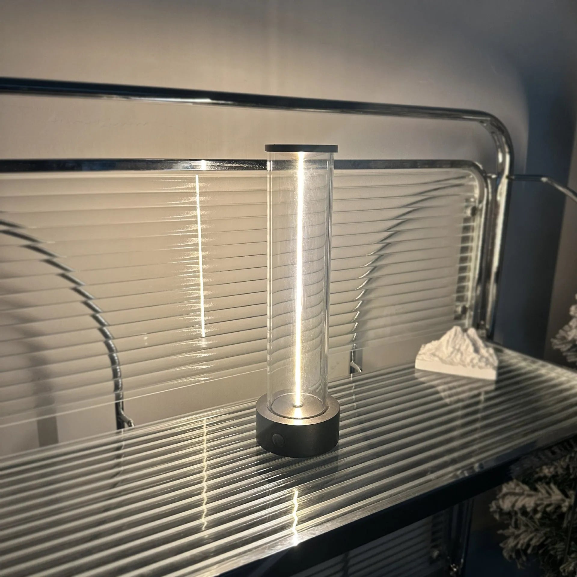 Tall cylindrical frosted glass USB rechargeable LED night light with a magnetic base on a wooden surface.