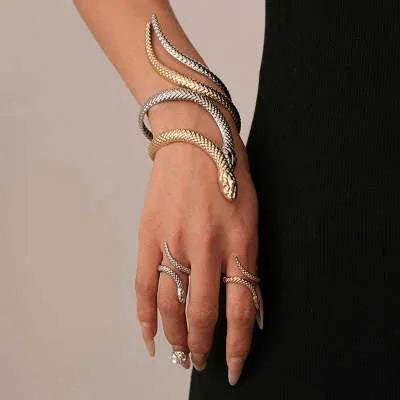 Gold exaggerated twisted snake design bracelet and ring jewellery set on a dark background.