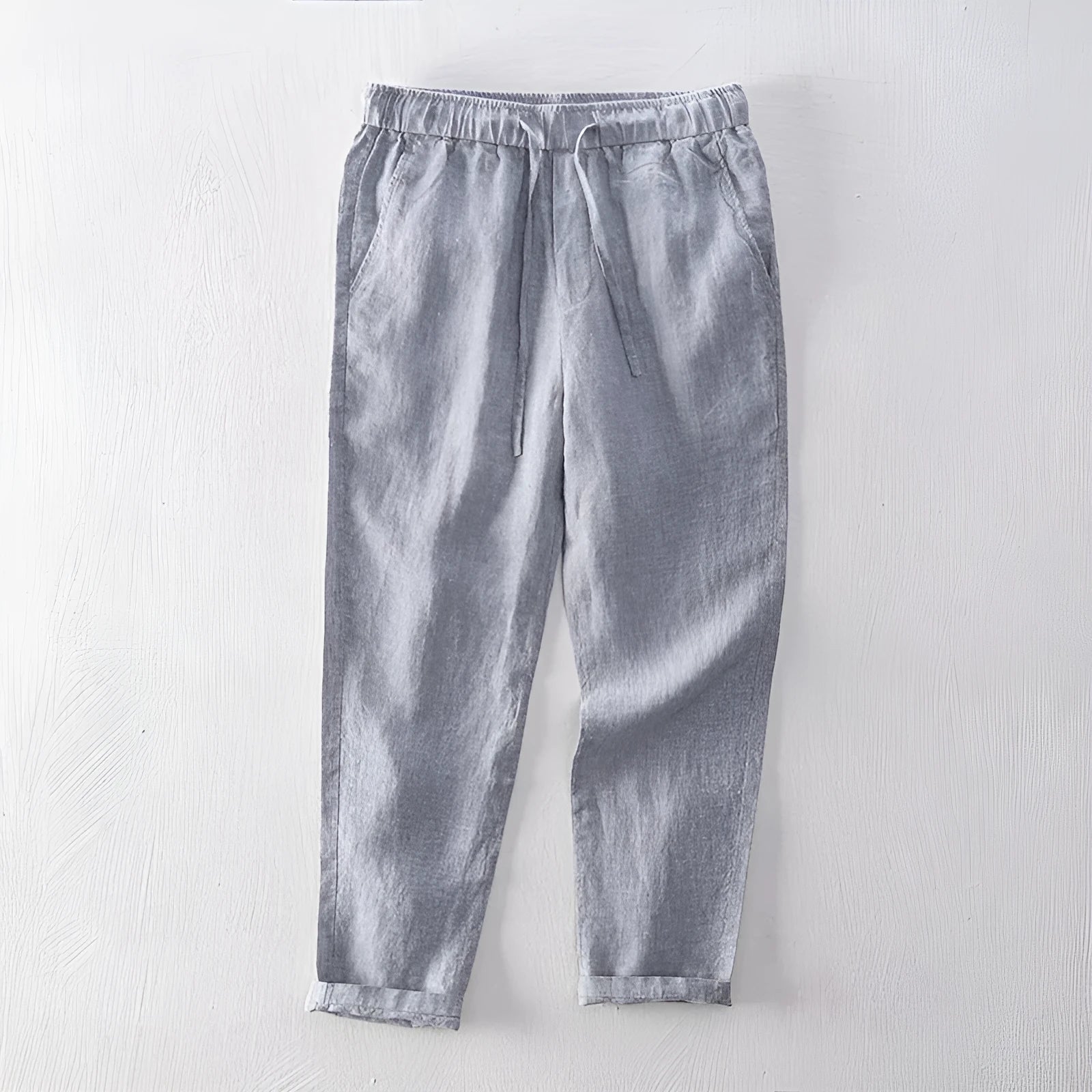 Men's straight-leg linen trousers in light gray shown laid flat.