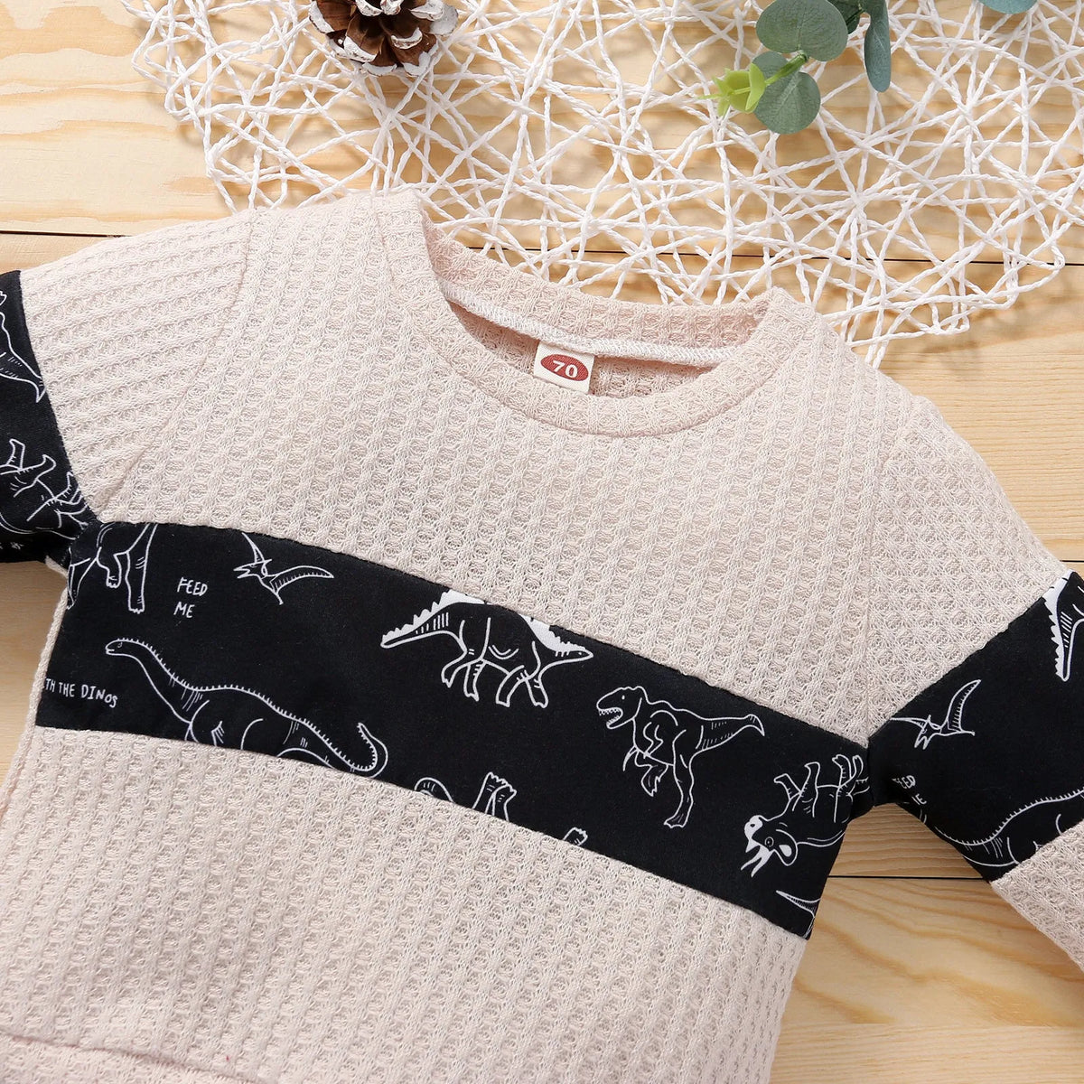 Cotton children's pants suit with dinosaur cartoon pattern in beige, pullover top and trousers set on child model