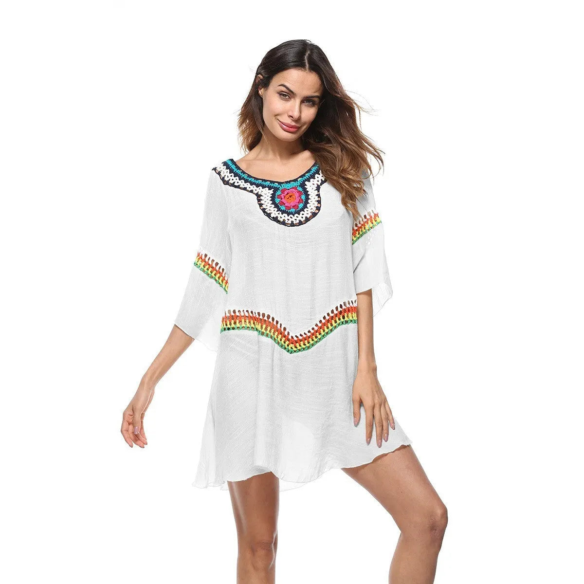 Woman wearing a crocheted white sun protection beach cover-up by the water.