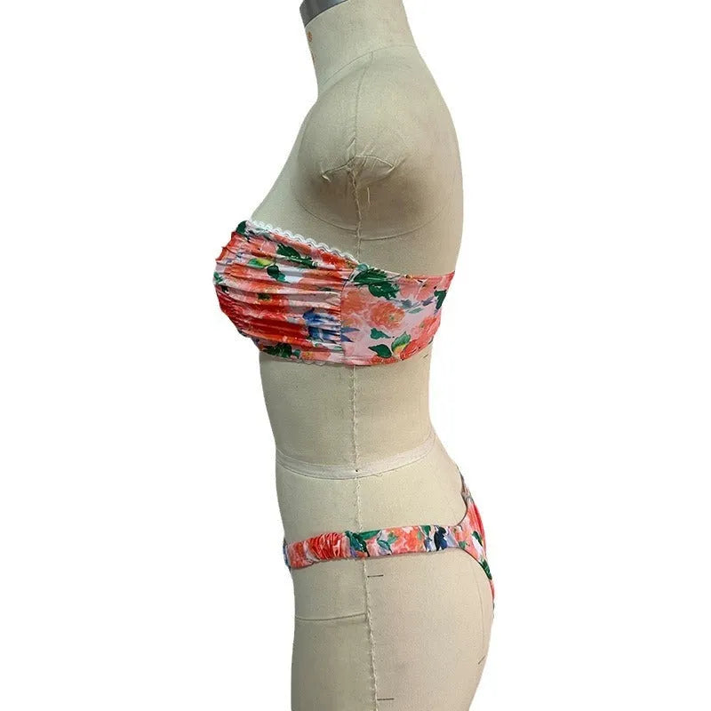Women's floral print tube top bikini set with lace detailing on a blue background.