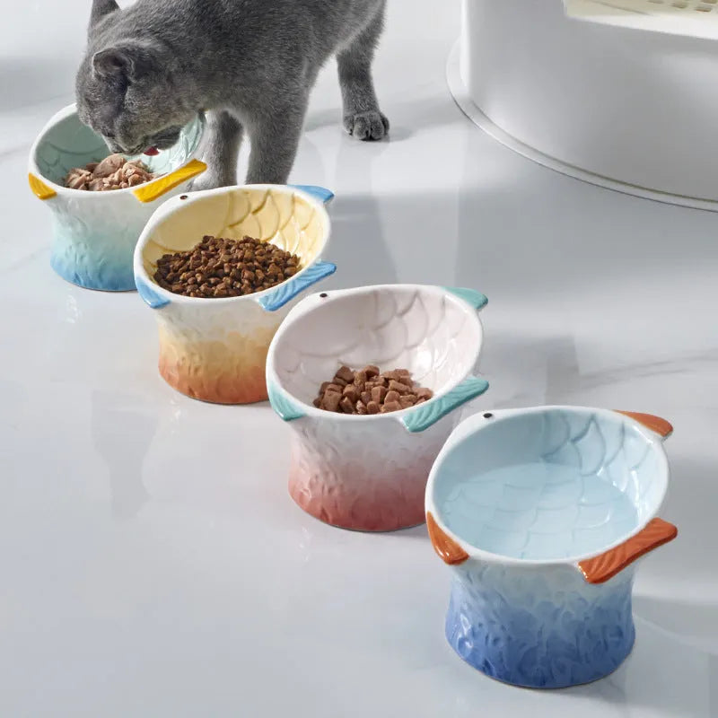 Set of four blue fish-shaped ceramic cat bowls with tilted, elevated design on a table.