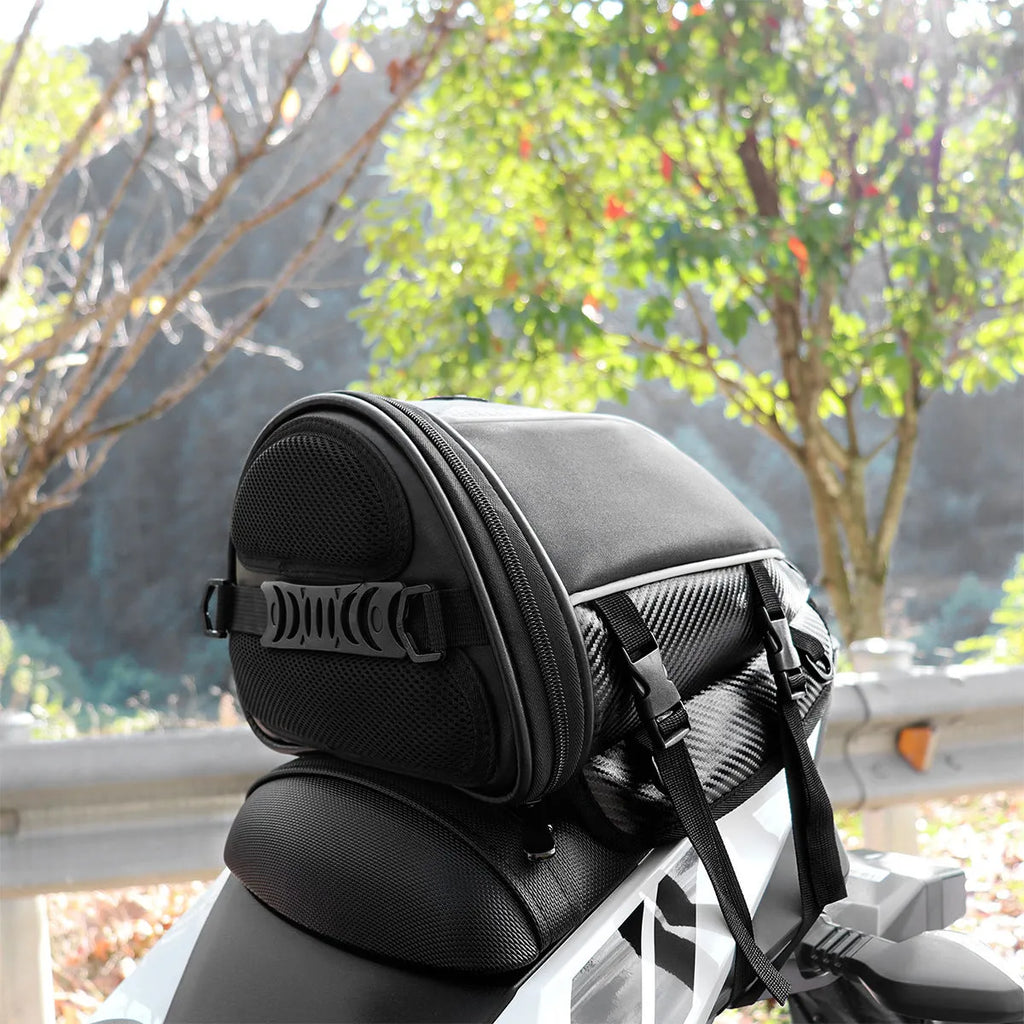 Black motorcycle seat bag with reflective strips, showing multiple pockets and an adjustable shoulder strap.