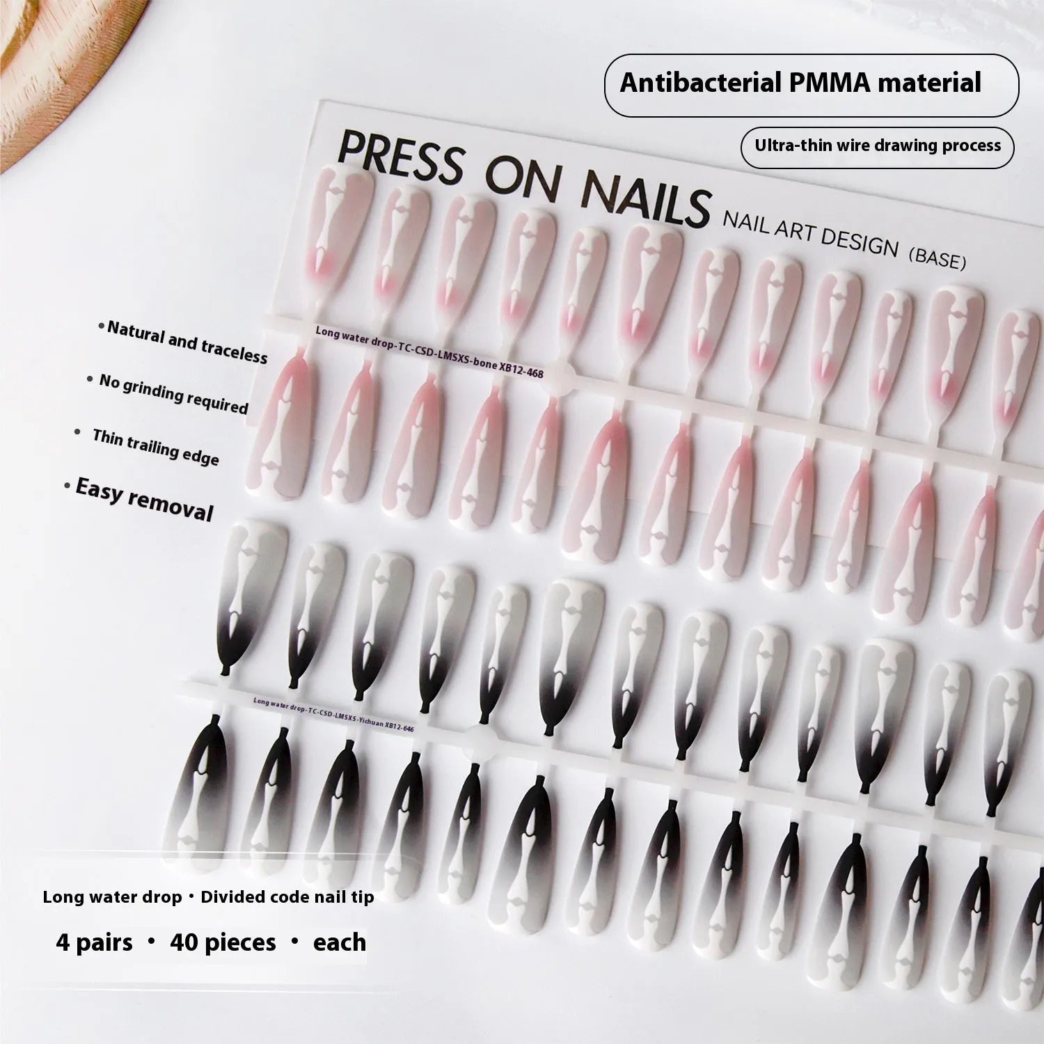 Close-up of long black and pink Christmas gothic nail tips with frosted finish on a flat surface, next to a storage strip.