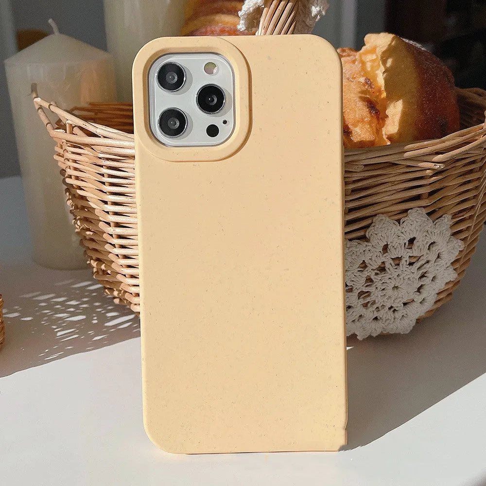 Degradable wheat straw phone case for Apple iPhone on a wooden surface.