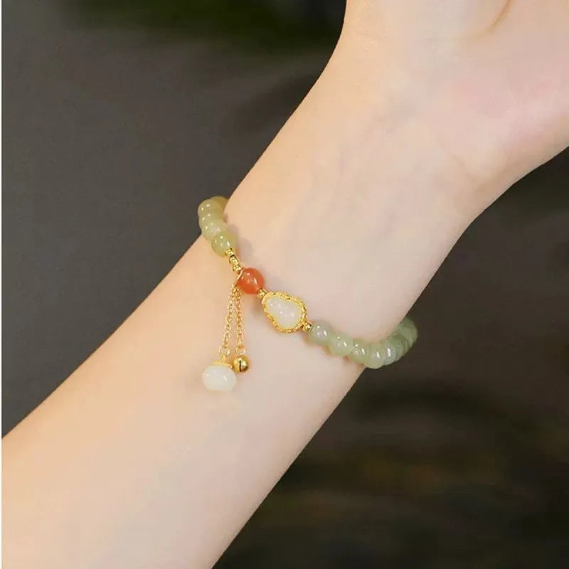 Women's jade bracelet with gold-plated gourd charm and Fu character pendant on a 6mm bead.
