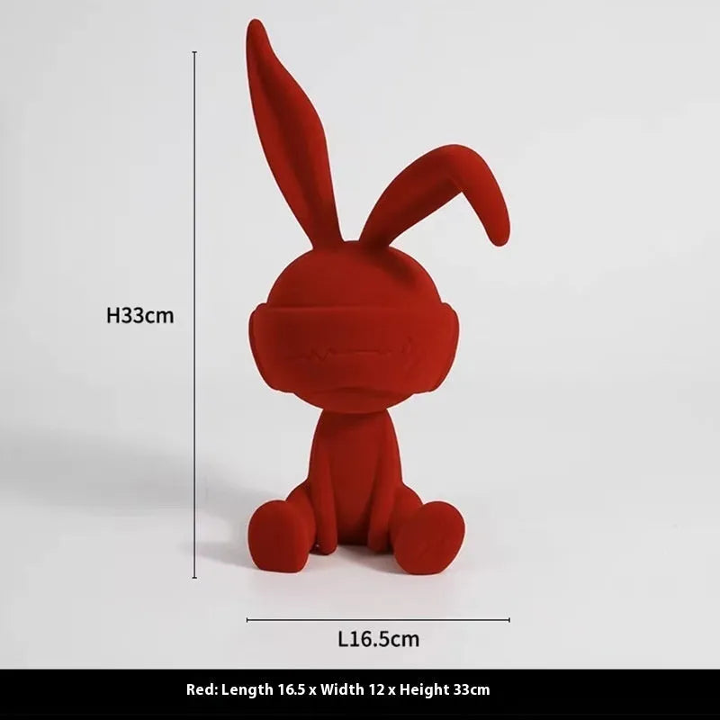 Green resin rabbit table ornament with suede blindfold on wooden surface