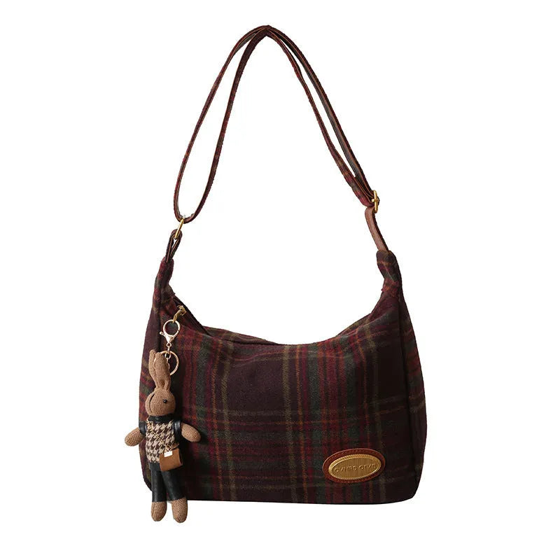 Red women's large wool shoulder bag with pendant on a table, showing square shape and sewing detail.
