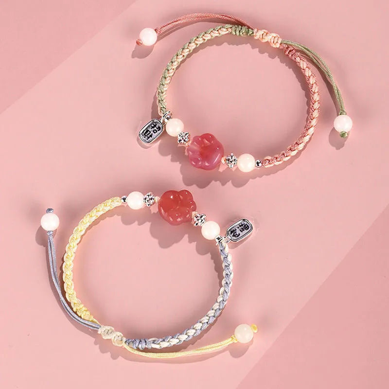 Red cat's paw glass bead on a handmade pink woven bracelet for couples.