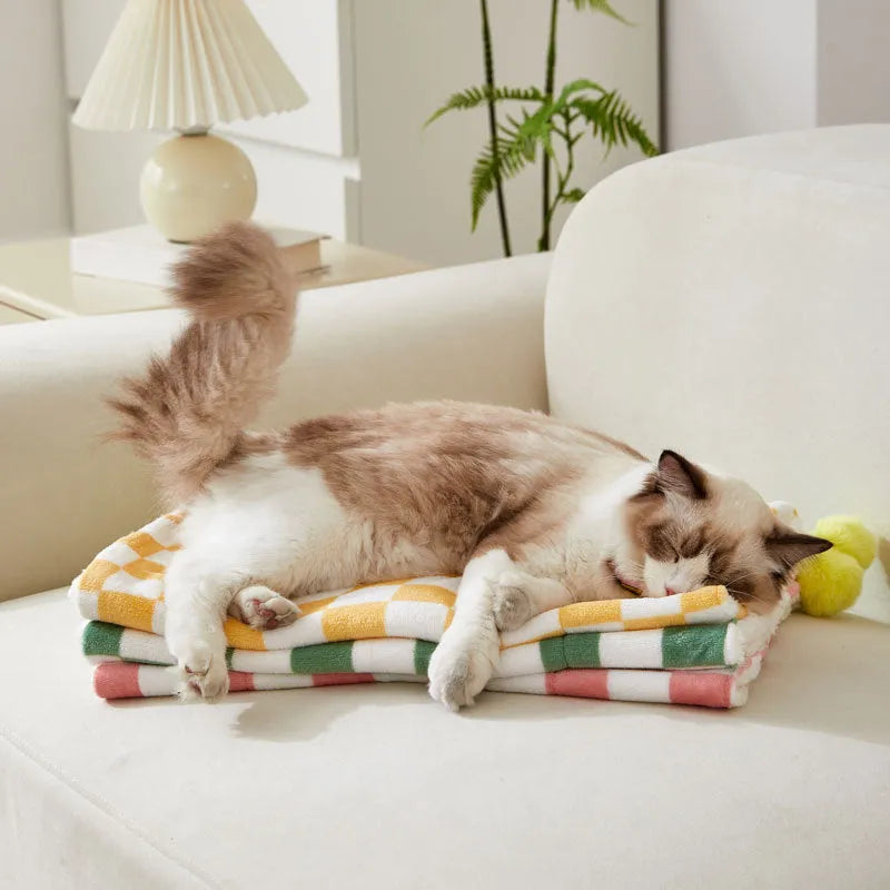 Soft plaid pattern pet blanket with fur ball decoration on a sofa