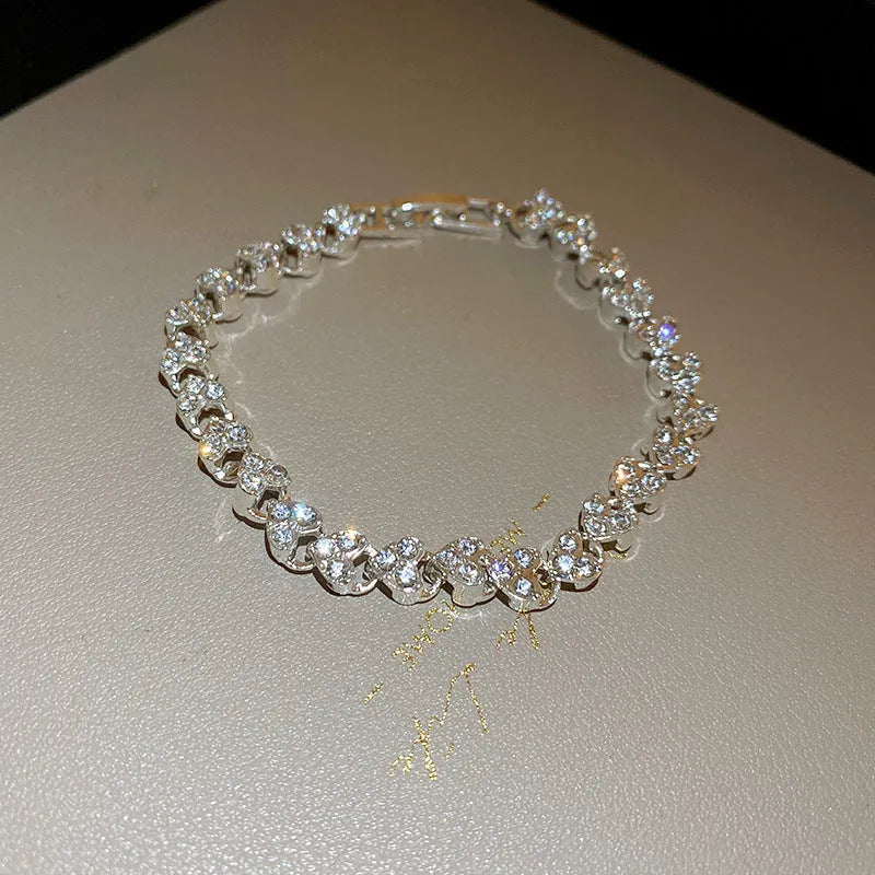 Silver metal heart-shaped bracelet with inlaid zircon on a plain background