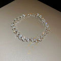Silver metal heart-shaped bracelet with inlaid zircon on a plain background
