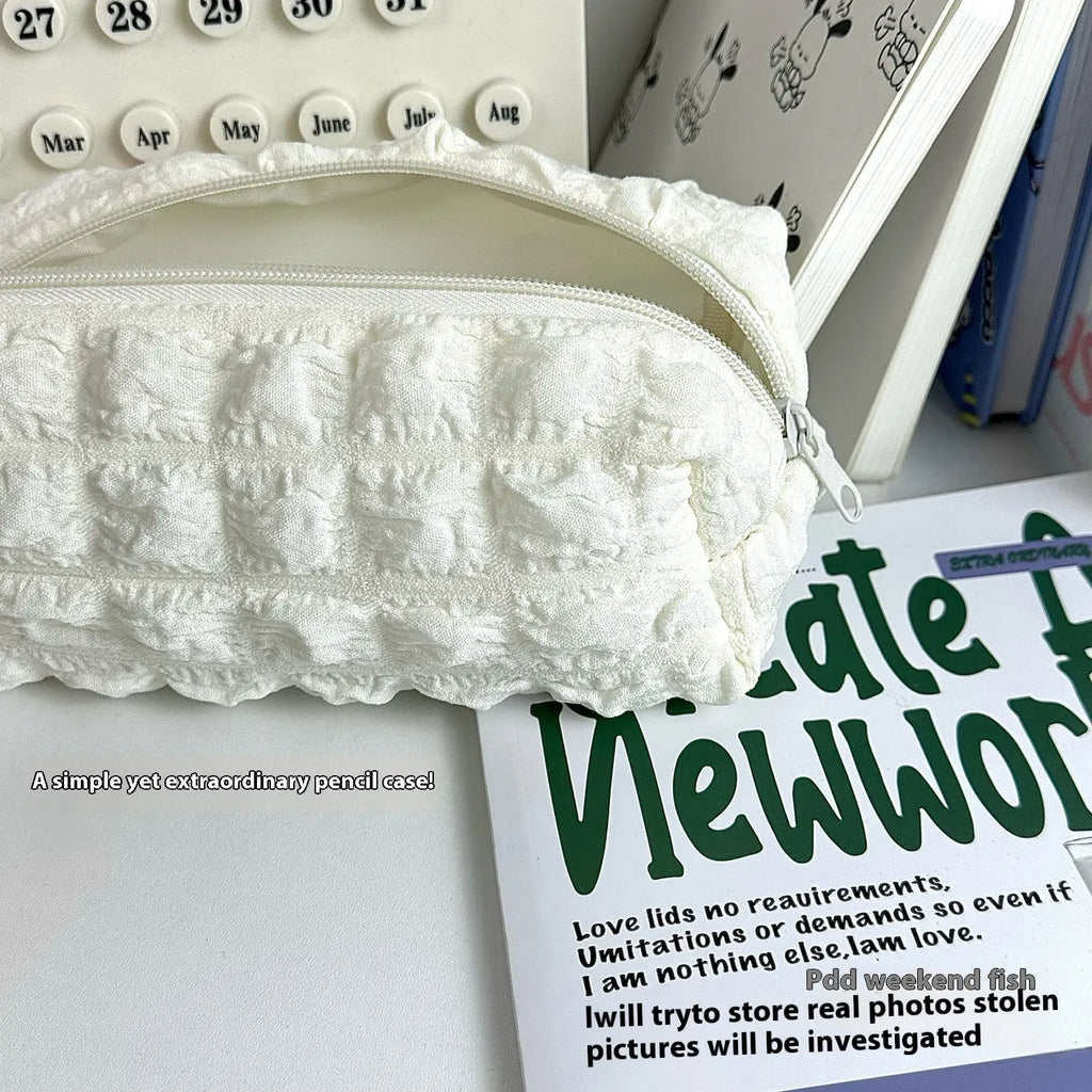 Cream puff style polyester fabric pencil case for pens, shown in beige and black colour options.