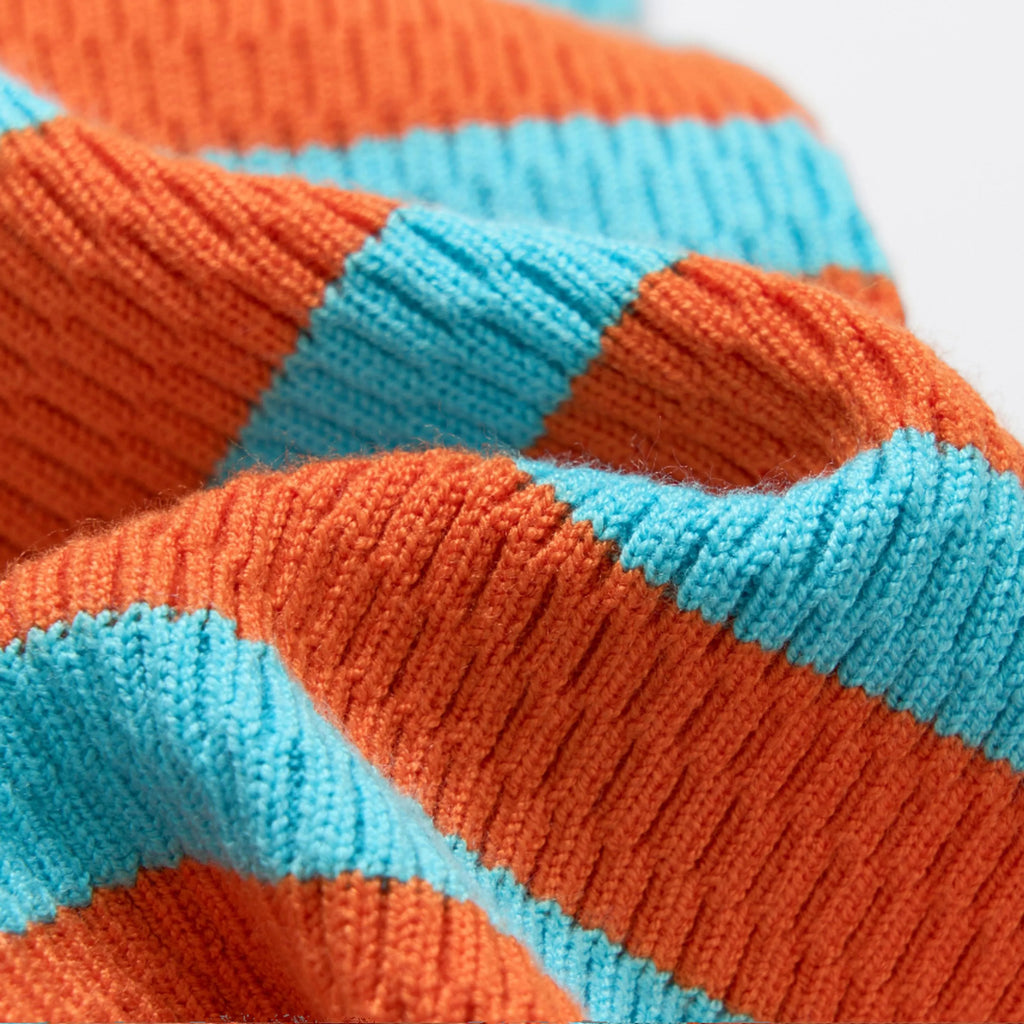 Knitted contrast colour stretch dog clothing in vibrant orange on a light background showing four-legged jumpsuit
