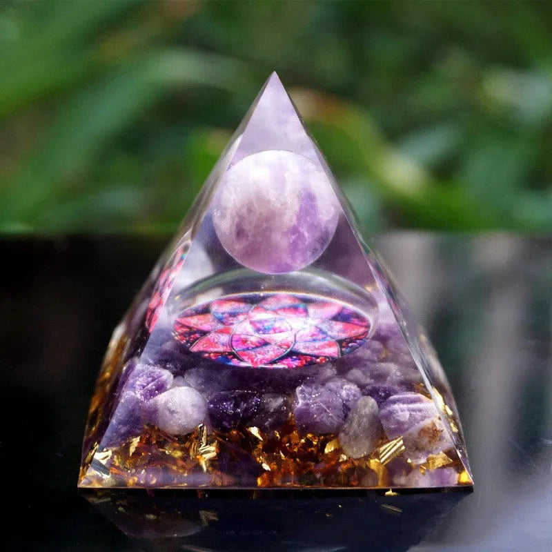 Clear epoxy resin pyramid ornament with natural crystal gravel inside on a wooden surface.