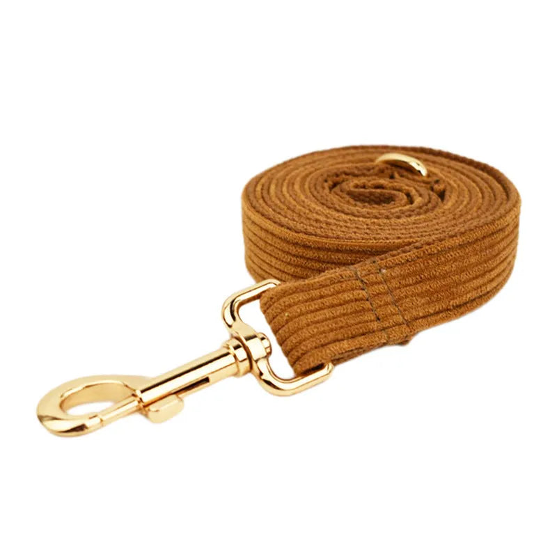 Caramel corduroy pet collar set with ring, rope, bow, vest, and poop bag on a light background