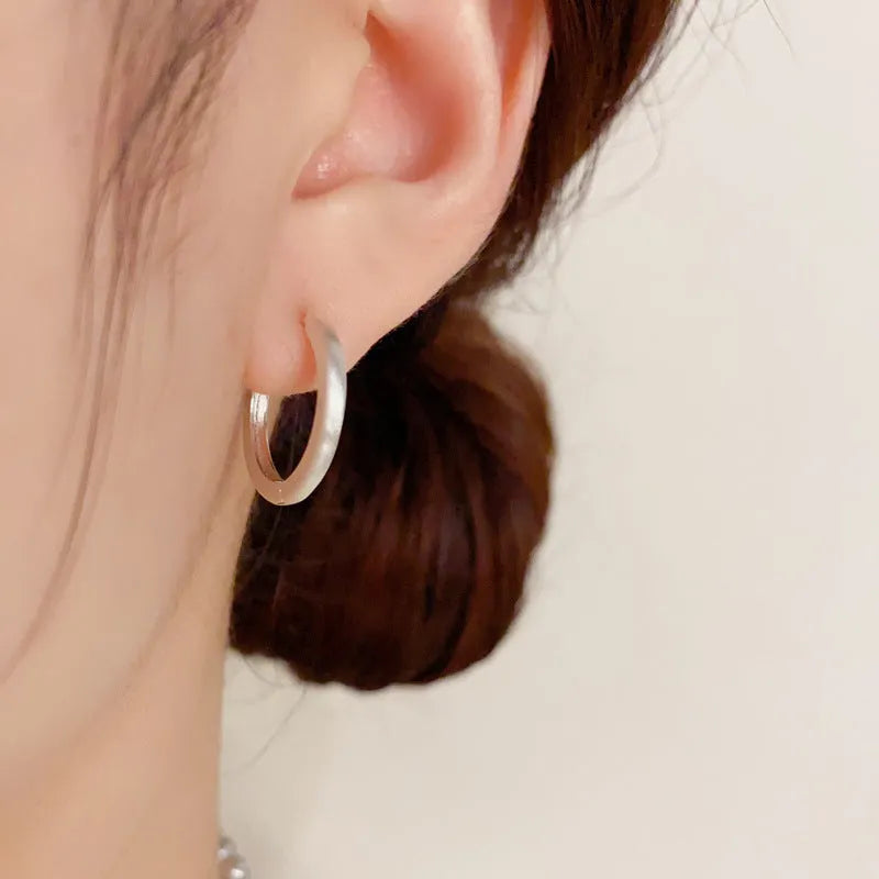 Women's geometric round eyelet ear clips in gold and silver colours, showing front view.